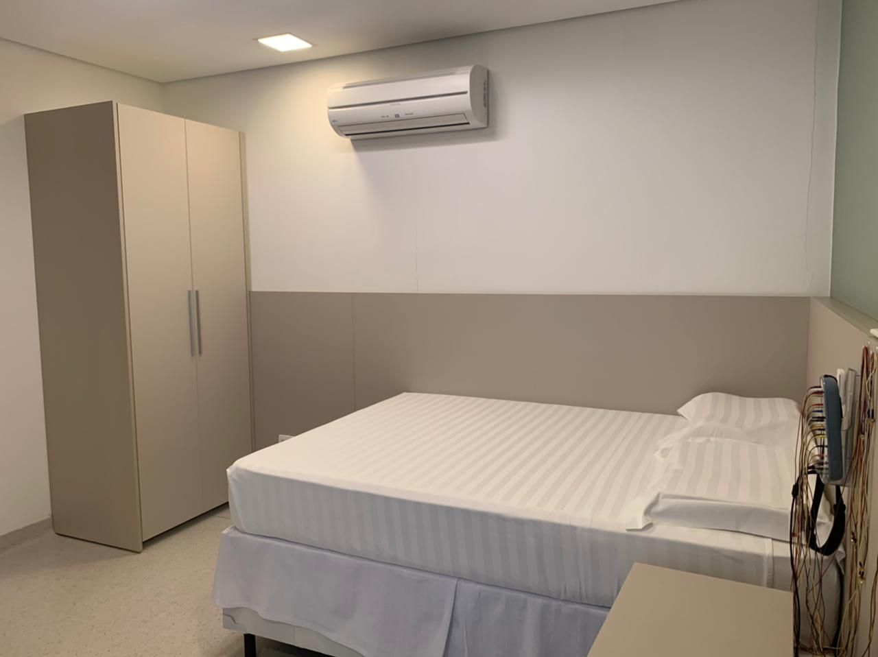 Suíte individual da clínica PolissonoNoLar com cama queen, ar-condicionado e banheiro privativo
